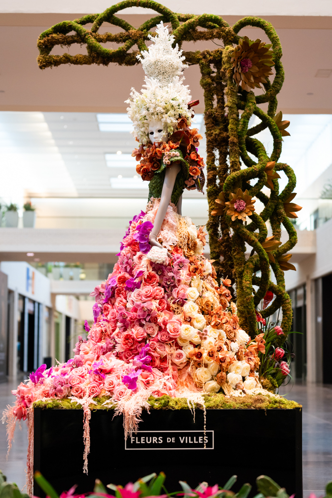 A vibrant floral mannequin on display at NorthPark Center, designed by a local florist for Fleurs de Villes ARTISTE. This piece, inspired by Dallas’s rich arts culture, showcases intricate blooms and bold colors—blending fashion, floristry, and fine art in a captivating, living installation. Photographed by Jennifer for Lightly Photography.